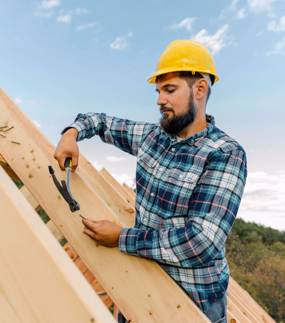 man hammering a piece of wood as part of construction job